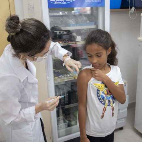 Enfermeira aplicando dose de vacina no braço de uma criança