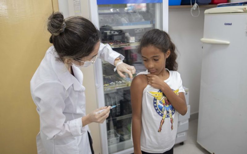 Enfermeira aplicando dose de vacina no braço de uma criança