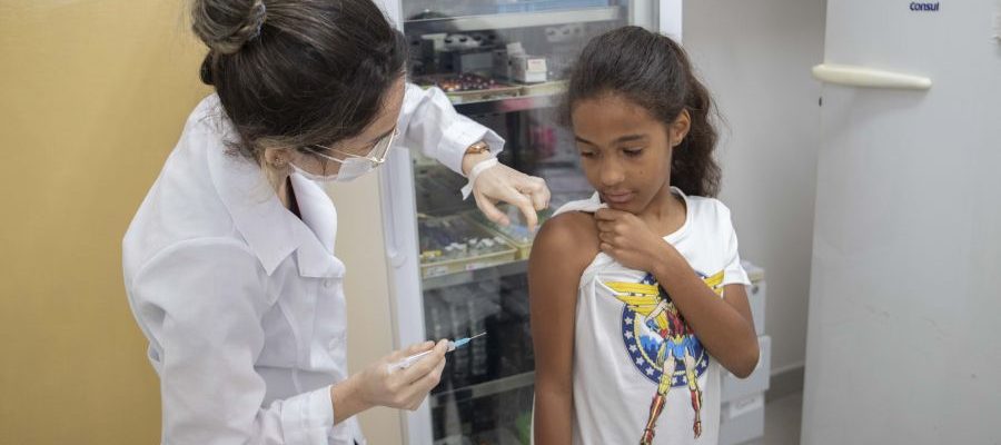 Enfermeira aplicando dose de vacina no braço de uma criança